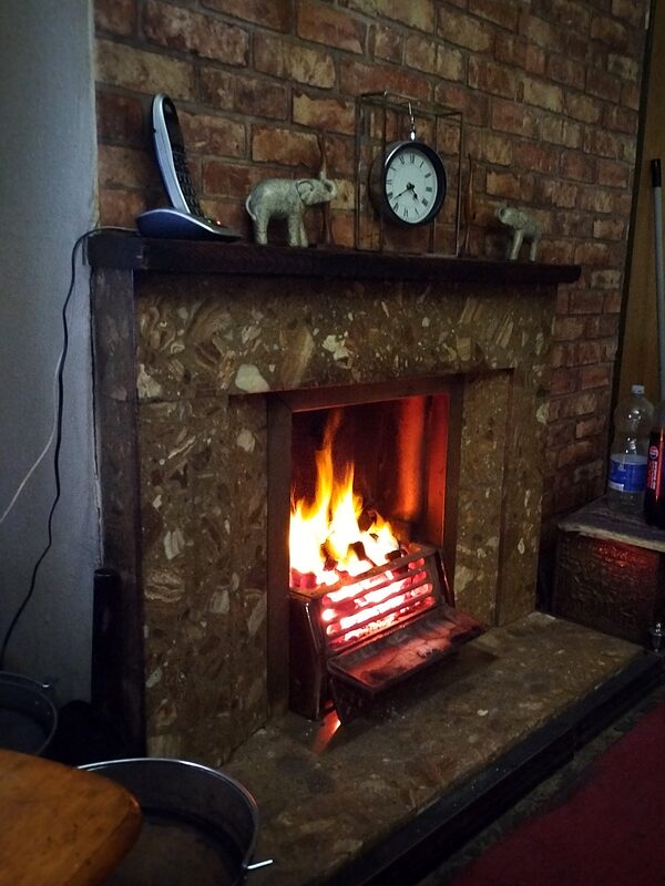 A fire burning in a brick fireplace with a clock on the mantel