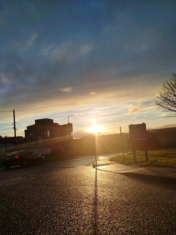 A wet road at sunset under a wide sky